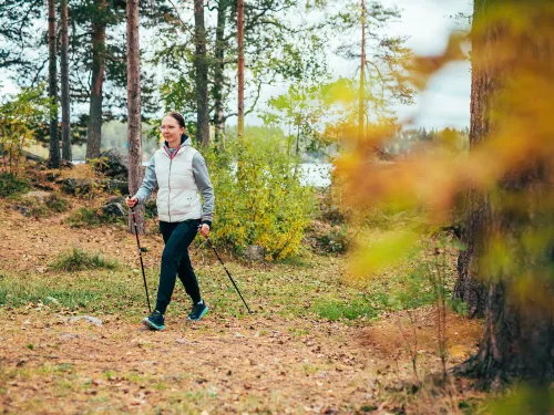 Naisen sauvakävelee syksyisessä metsässä.