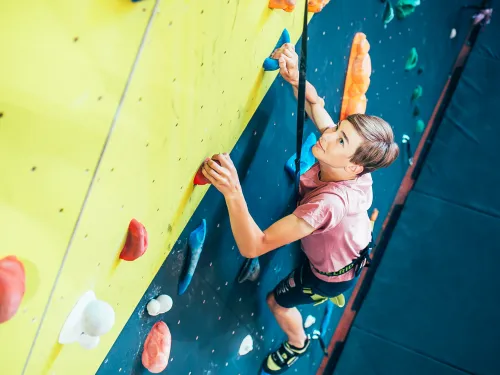 Nuori poika seinäkiipeilemässä turvaköyden varassa.