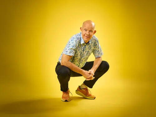 Kaj Kunnas poseeraa iloisena keltaisen taustan edessä