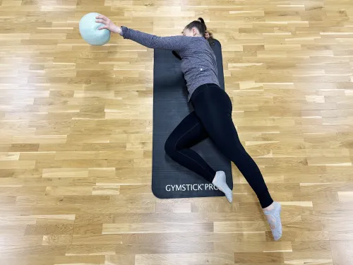 Pilates-ohjaaja venyttelee jumppamatolla pilates-pallon kanssa.
