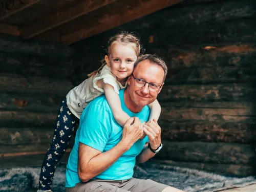 Isä ja tyttö hymyilevät laavulla.