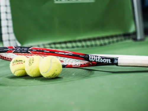 Tennis racket and three balls on a green court.
