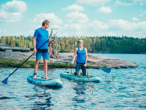 Mies ja nainen sup-lautailemassa järvellä.
