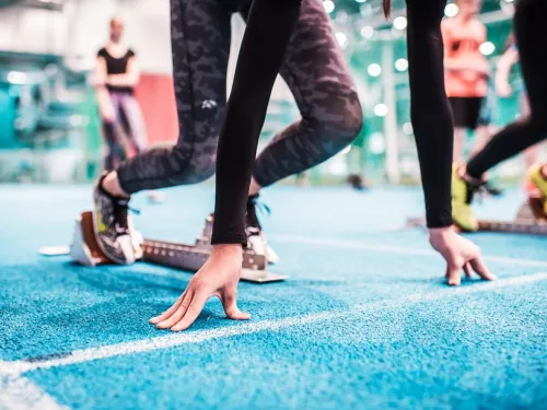 Athletes in starting blocks on an indoor blue track.