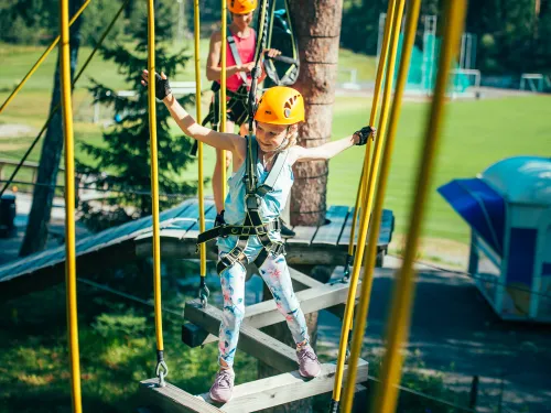 Tyttö tasapainoilee puussa olevalla esteradalla Pajulahden Seikkailupuistossa