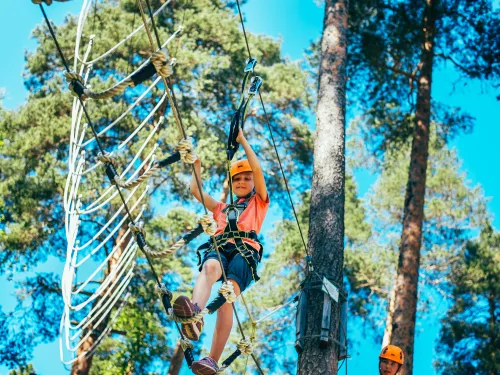 Nuori kiipeilee Pajulahden Seikkailupuiston puussa roikkuvalla radalla
