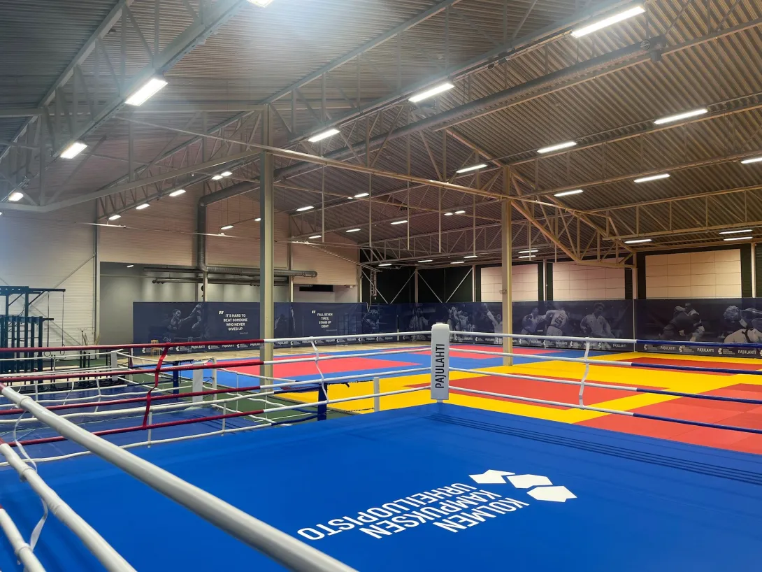 Pajulahden kamppailuareena. Sisähallissa värikkäitä voimistelumattoja ja nyrkkeilykehä, valaistus katossa.
