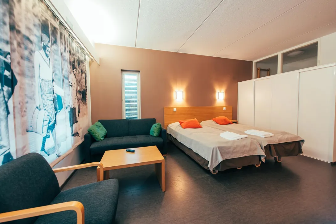 Moderni hotellihuone, jossa on parivuode, sohva ja pöytä.